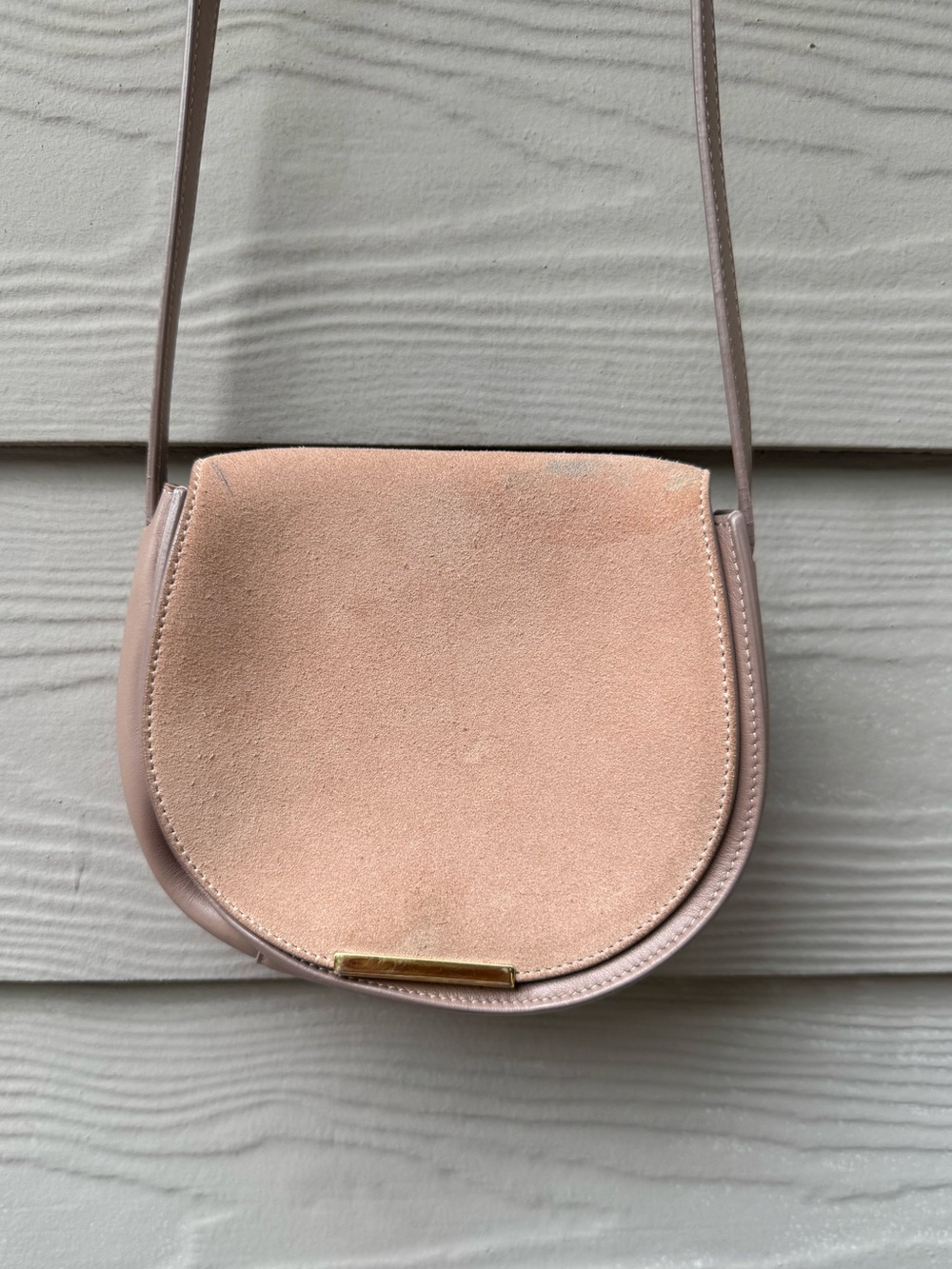 Cuyana saddle bag features a blush pink suede front flap and gold hardware